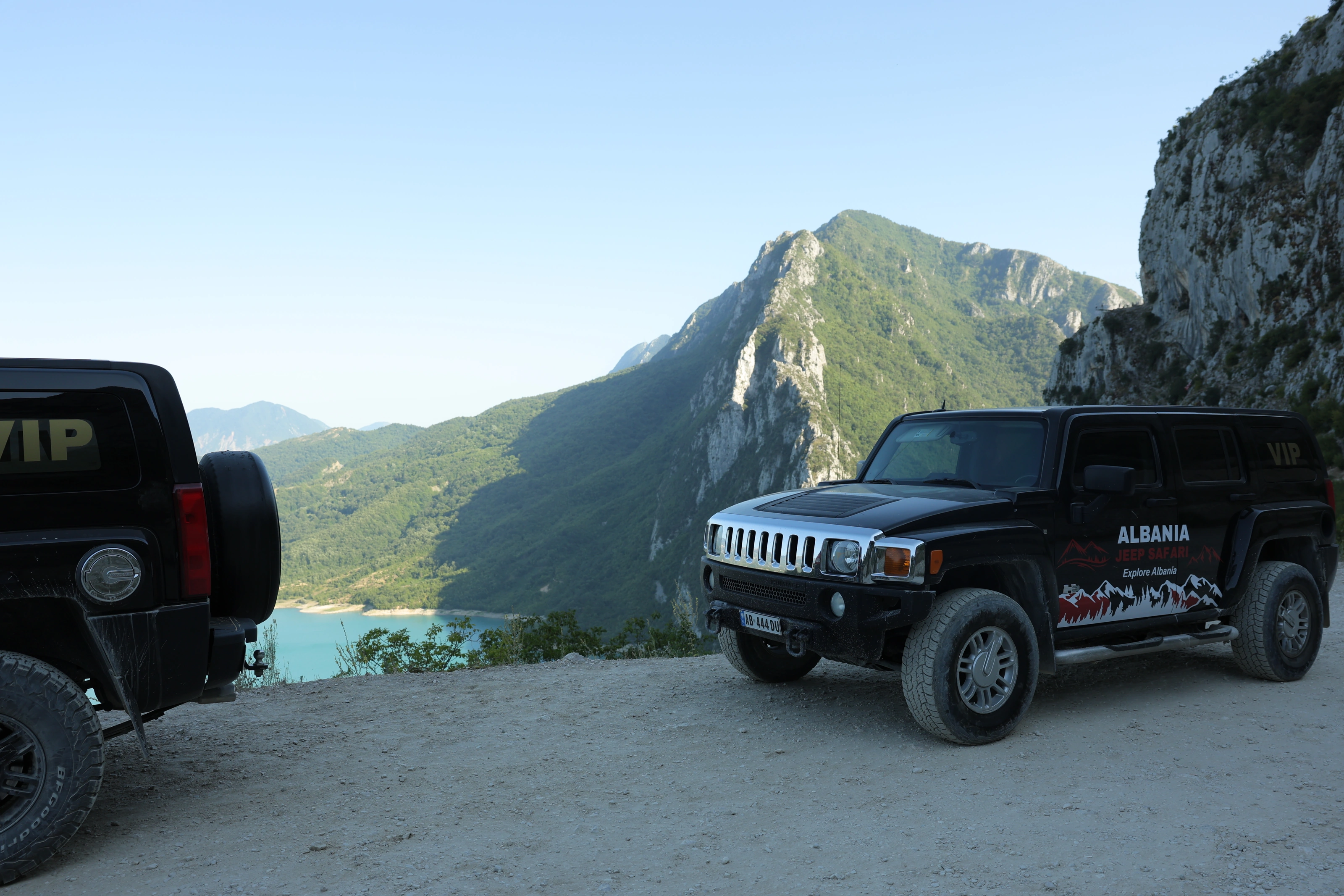 Hummer H3 parked above the turquoise lake, peaks behind