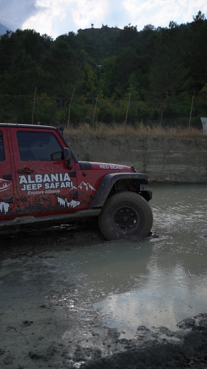 Red Albania Jeep Safari Wrangler on the gravel by the river