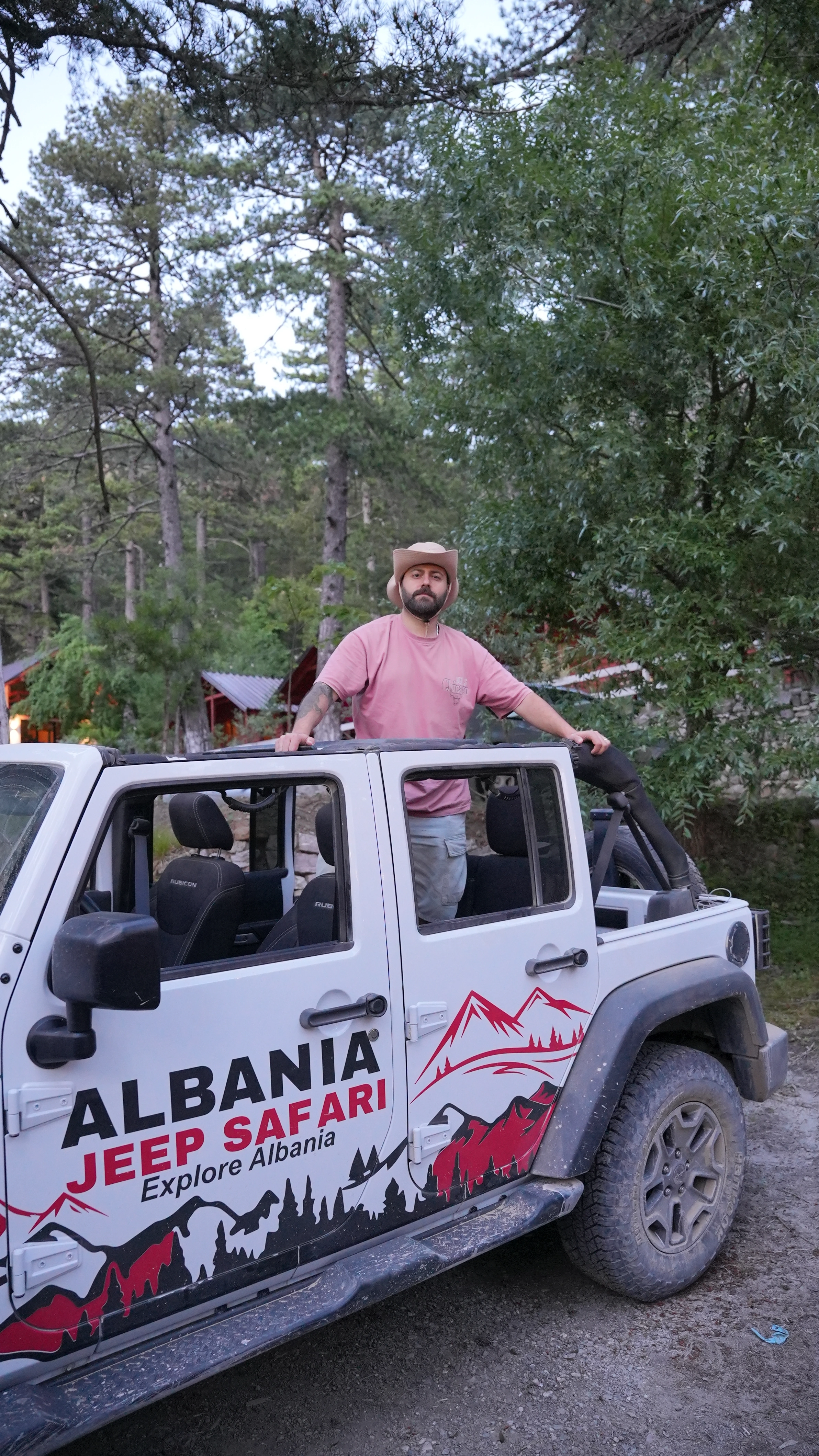 Guest standing up through the open roof of a Wrangler in the pine forest
